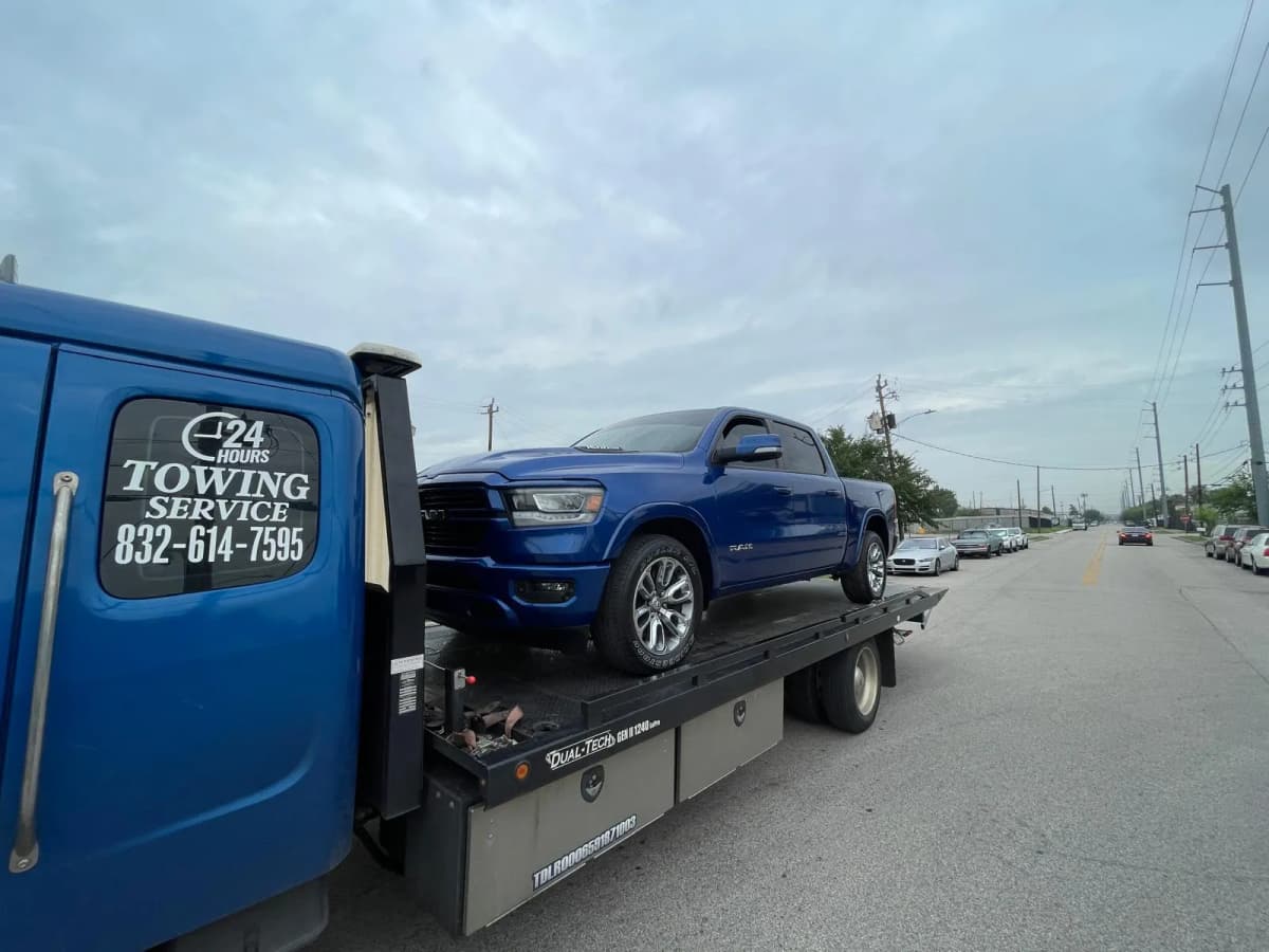 RAM 1500 Truck Towing - Houston TX Blue RAM 1500 pickup truck on flatbed tow truck in Houston TX