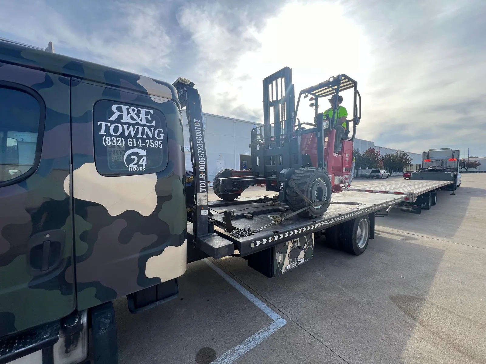 Forklift loaded on flatbed tow truck for equipment transport in Houston TX