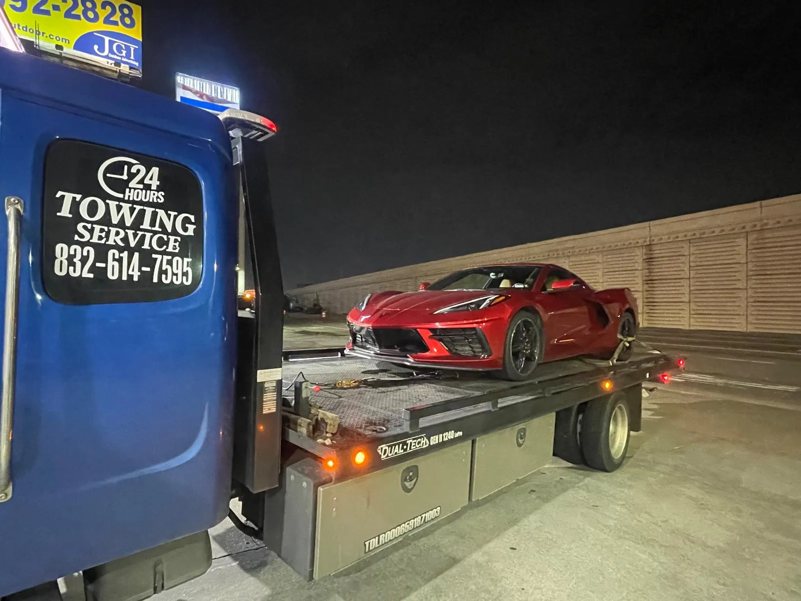 Red Chevrolet Corvette C8 on flatbed tow truck at night in Houston TX