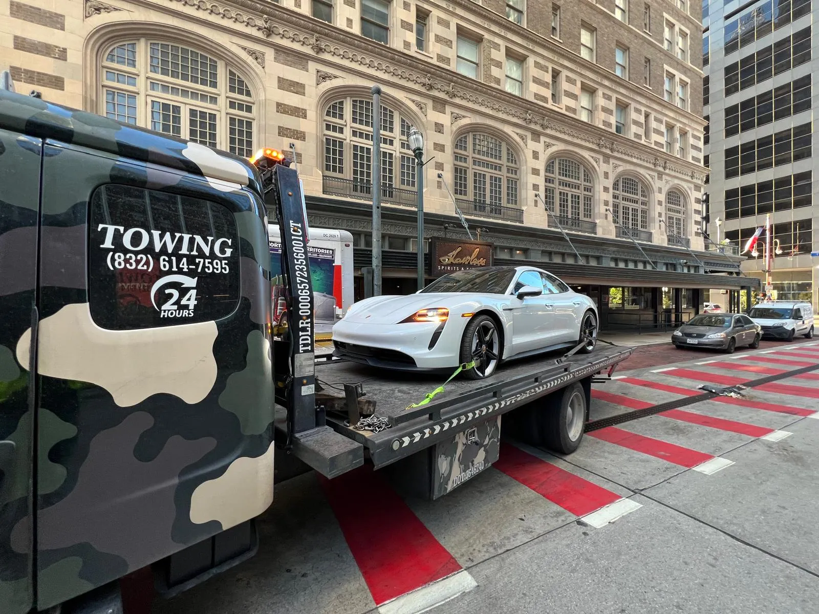Porsche Taycan electric car on flatbed tow truck in downtown Houston TX