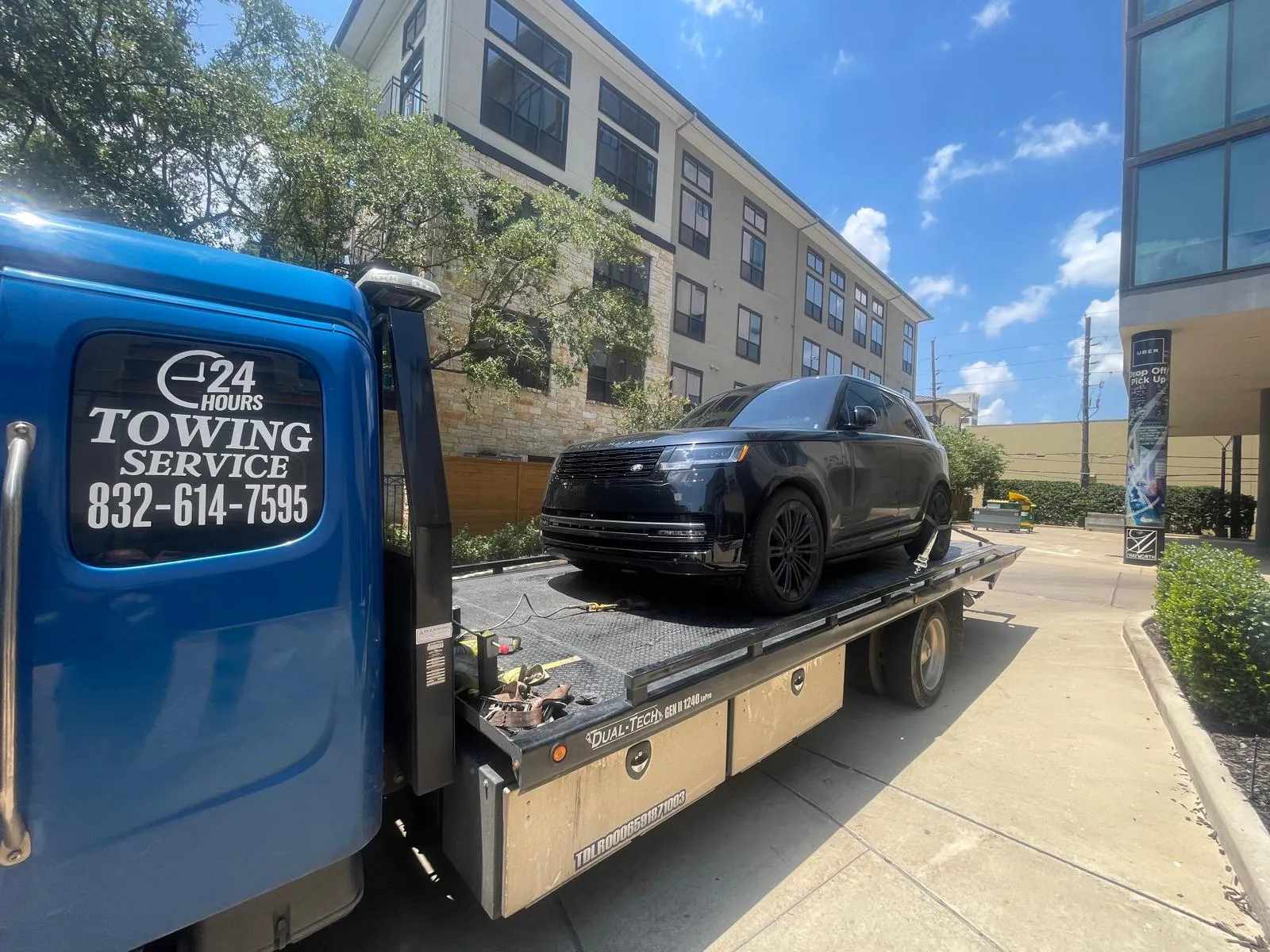 Black Range Rover on flatbed tow truck near commercial building in Houston TX