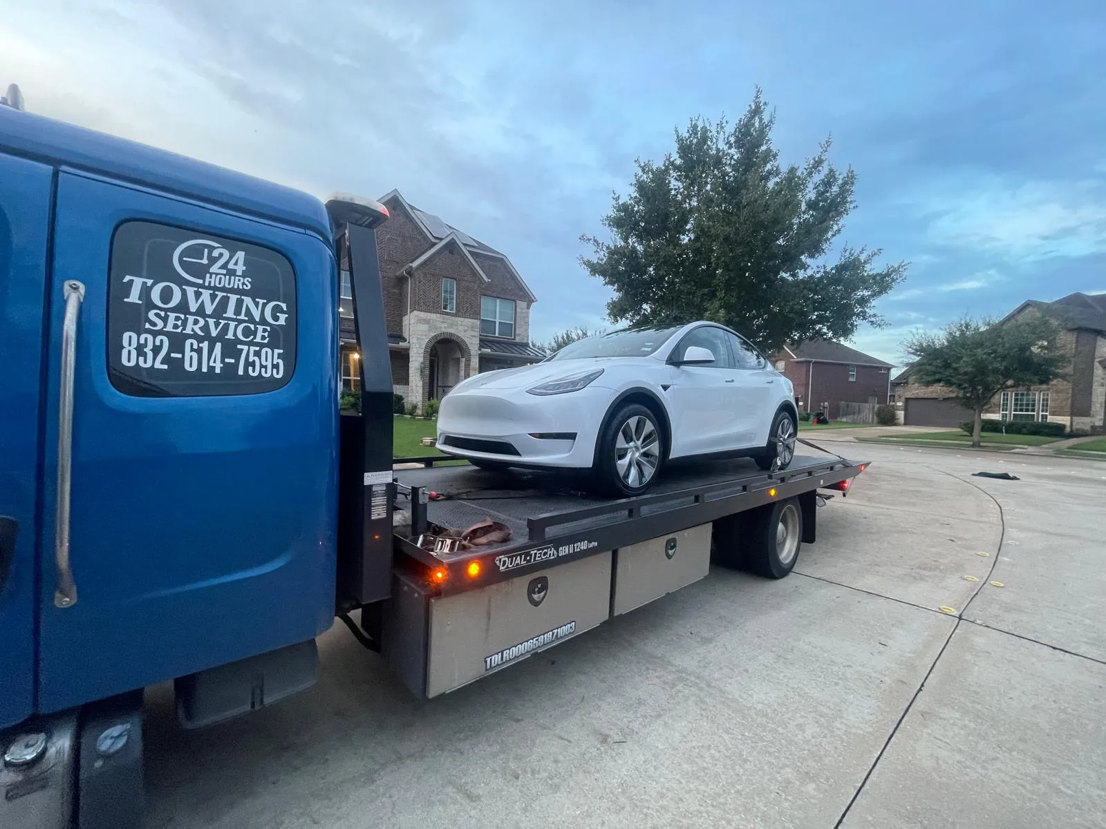 Tesla Model 3 safely loaded on flatbed tow truck in Houston TX residential neighborhood
